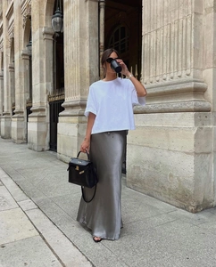 Elegant street style detail of a high-waisted silver satin midi skirt with white t-shirt