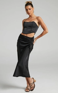 Detail of black satin skirt with side ruching and glossy finish high waist design