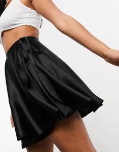Detail of high-gloss black satin wrap skirt with delicate waist tie and silky texture