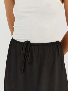 Detail of high waist drawstring on satin midi skirt with ribbed white crop tank top