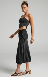Detail of black satin two-piece set featuring a structured corset top and ruched midi skirt