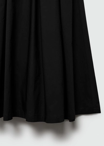 Detailed view of the pleated black midi skirt hem featuring fine machine edge stitching