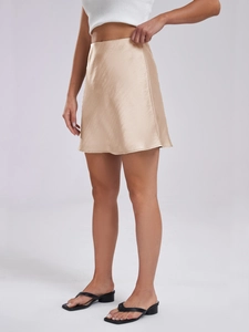 Detailed view of champagne gold satin mini skirt with smooth silk texture and high waist