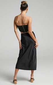 Detail of a sleek black satin two-piece set featuring a back zipper and high-waist skirt