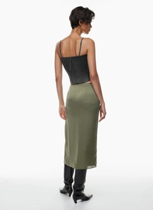 Rear view of an olive green satin midi skirt paired with black boots and a bodice top