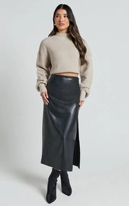 Détail d'une jupe midi en cuir PU à taille haute, fente latérale et pull en tricot