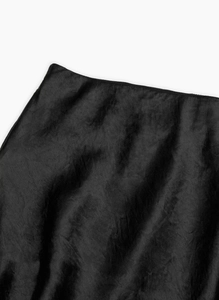Macro shot of high-shine black satin skirt fabric and seamless high waist detail