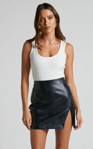 Detail of high waist black PU leather mini skirt with side slit and ribbed white tank top