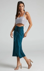 Detailed close-up showing the smooth teal satin texture and side drawstring ruching of the skirt