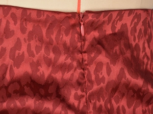 Détail d'une jupe en satin imprimé léopard rouge avec fermeture à glissière invisible de qualité