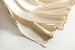 Macro view of champagne acetate satin skirt showing high gloss texture and fine stitching