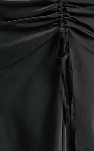 Close-up of black satin skirt featuring elegant drawstring ruching and silky fabric texture