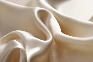 Close-up of champagne acetate satin fabric with pearl-like luster and soft drape