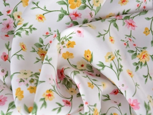 Close-up of lightweight white satin fabric with pink and yellow floral patterns