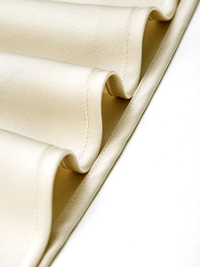 Gros plan du tissu en satin beige montrant des coutures de qualité et une texture soie