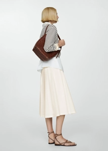 Brown woven leather shoulder bag styled with a pleated skirt and striped shirt