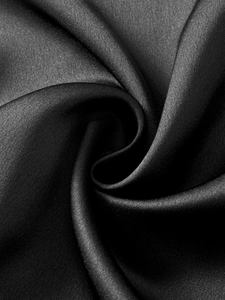 Vista macro del tessuto di raso nero liscio con lucentezza elegante e pieghe di seta