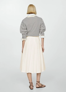Rear view of pleated cream midi skirt paired with striped knitwear in French chic style
