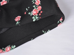Macro view of satin skirt fabric featuring red rose print and twill texture details