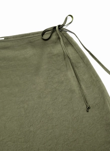 Detail of army green satin skirt featuring smooth fabric texture and lace-up waist tie