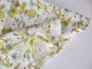 Close-up of floral print satin fabric with detailed white overlock stitching on the hemline