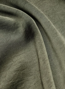 Detailed macro view of olive green satin fabric showing diagonal twill weave and soft texture