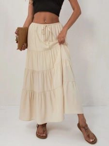 Détail d'une jupe longue à volants en coton beige avec taille haute élastique à cordon