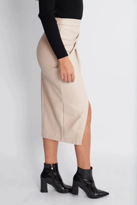 Detail view of high waisted beige PU leather midi skirt with side slit on a model