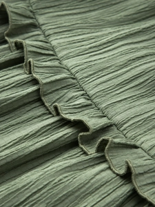 Détail du tissu plissé vert olive avec un motif à volants délicat et une texture froissée