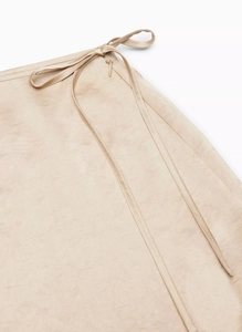 Close-up of champagne satin midi skirt showing high-waisted wrap tie and premium fabric texture