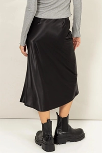 Détail d'une jupe midi en satin noir à taille haute avec fente latérale et texture soie