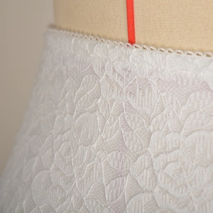 Dettaglio macro di elegante pizzo bianco con trame a rete e motivi floreali ricamati
