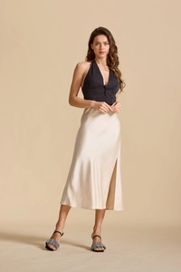 Détail d'une jupe en satin champagne à taille haute avec fente latérale et tissu soyeux