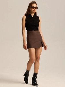 Detail view of high waisted brown mini skirt with a side slit and sleek tailored fit