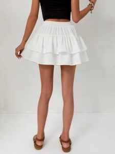 Detail view of white layered ruffle mini skirt featuring high waist elastic band texture