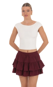 Detail of burgundy layered ruffle skirt featuring tie waist and floral textured fabric