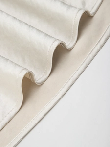 Detail view of champagne satin fabric showing fine stitching and smooth silk texture