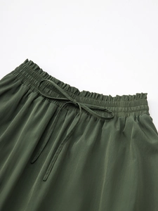 Detailed close-up of ruffle elastic waistband and drawstring on dark green skirt