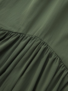 Detailed close-up of dark green flowing fabric with ruffled edges and soft texture