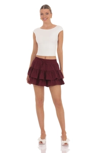 Detail of burgundy tiered mini skirt with elastic drawstring waist and white crop tank top