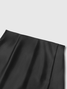 Dettaglio della vita di una gonna in raso nero con tessuto setoso e drappeggio elegante
