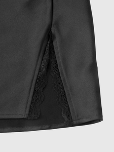 Dettaglio dello spacco laterale con pizzo su un'elegante gonna in raso nero