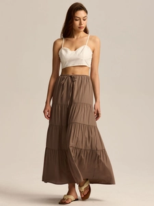 Vue détaillée du crop top blanc et de la jupe longue à volants marron avec cordon