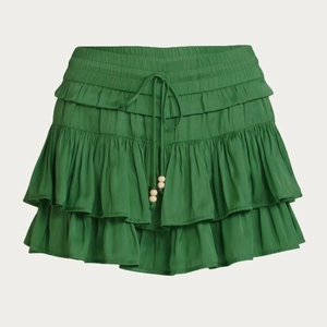Detail of green tiered ruffle mini skirt with drawstring waist and wooden beads