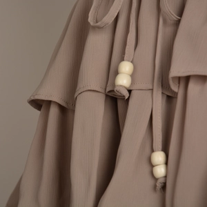 Detail of tiered chiffon skort with ruffled layers and drawstring with wooden beads