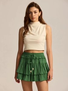 Detail of green tiered skort with drawstring waist and wooden bead accents on fabric