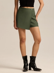 Detail view of dark green wrap skort with decorative button and structured fabric finish