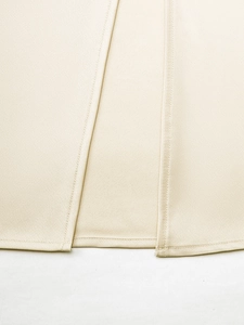 Détail d'une jupe en satin beige montrant la texture lisse et la fente cousue avec précision