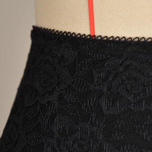 Dettaglio macro del pizzo floreale nero con bordi smerlati su una minigonna aderente