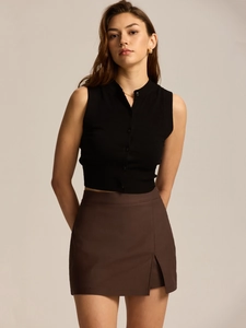 Detail of high waist brown suit skirt with side slit paired with a black knitted vest